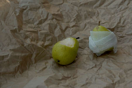 idea sick wounded pear wrapped with bandage on brown backgroundの写真素材