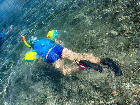 little boy diving in the sea in blue water on a summer warm holiday dayの写真素材