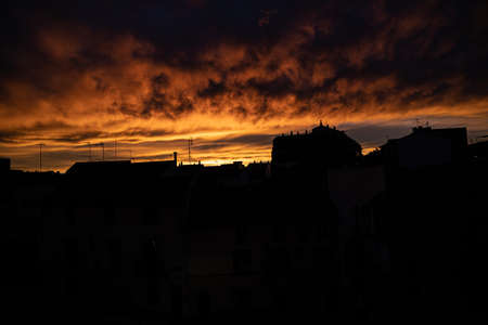 beautiful sky background with clouds after sunset over dark rooftops