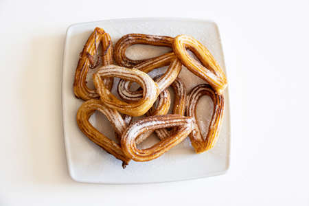 fresh, tasty, crunchy Spanish churros with sugar and cinnamon on a white plate