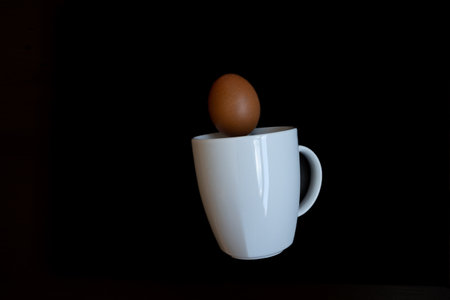 a few eggs falling into a white cup on a black background easterの写真素材