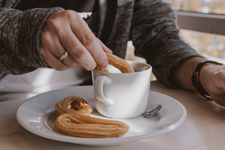close-up of a man eating a typical sweet Spanish breakfast and churros with chocolateの写真素材