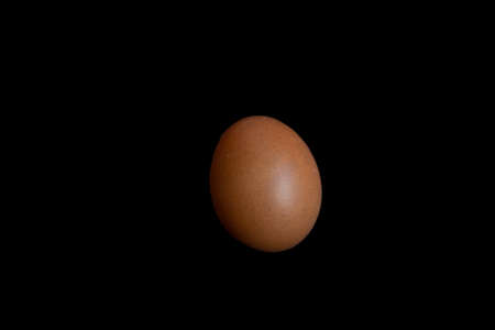 large brown hen egg on a black background close-up