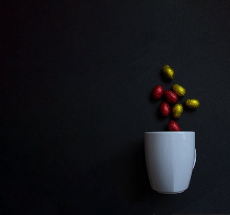 a few eggs falling into a white cup on a black background easterの写真素材