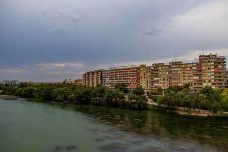 landscape of the Ebro river and apartment blocks in Zaragoza, Spain on a cloudy summer dayの写真素材