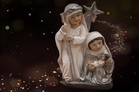 beautiful ceramic figurines of the mother of God joseph and baby jesus for the nativity scene on a dark brown backgroundの写真素材