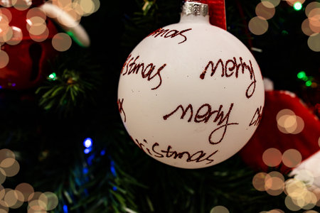beautiful white bauble with red inscription merry christmas on a festive backgroundの写真素材