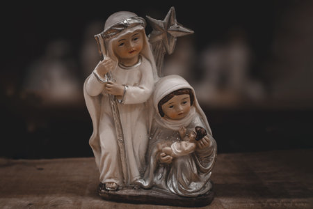 beautiful ceramic figurines of the mother of God joseph and baby jesus for the nativity scene on a dark brown backgroundの写真素材