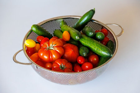 beautiful fresh healthy organic tomatoes and cucumbers in strainerの写真素材