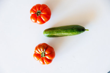 beautiful tomato and green cucumber on a white backgroundの写真素材