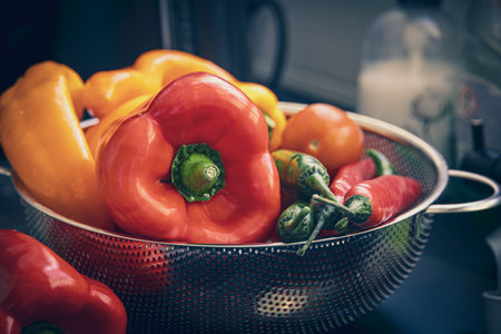 colorful ripe large peppers on a strainer in the kitchenの写真素材
