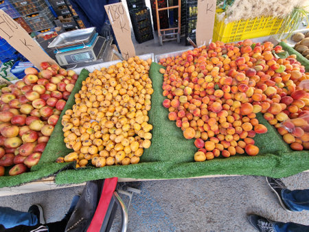 A variety of fruits, including apples, peaches, and apricots, are displayed on a market stall.の写真素材
