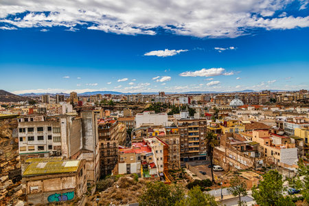 A sprawling urban Cartagena landscape is set under a vibrant blue sky dotted with fluffy cloudsの写真素材