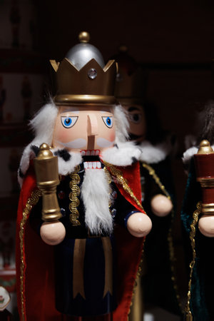 A wooden nutcracker soldier wearing a regal crown and a red cape is prominently displayed, holding a gold staff.の写真素材