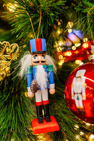 A festive nutcracker ornament hangs on a decorated Christmas tree,の写真素材