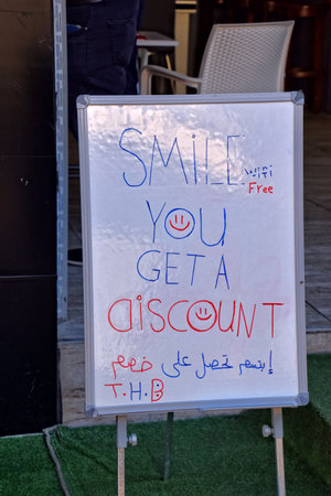 A sign outside a café advertises discounts for smiling customers, with cheerful red and blue handwritingの写真素材