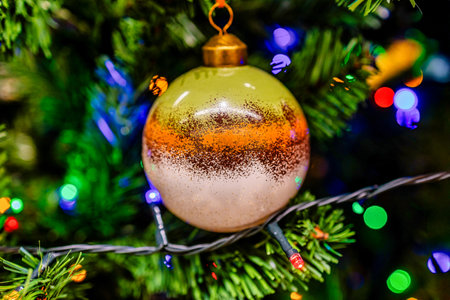 ornament with a leaf design hangs on a Christmas tree, surrounded by lush green branchesの写真素材