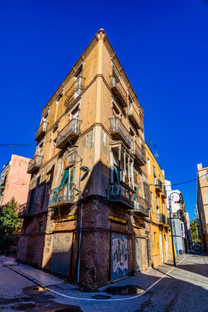 A tall, narrow building stands at the intersection of two streets under a clear blue sky spain Cartagenaの写真素材