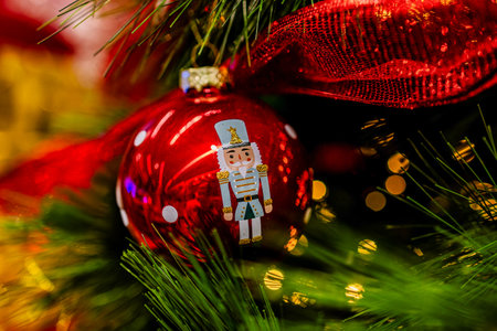 A festive red ornament featuring a nutcracker design hangs amidst green pine branchesの写真素材