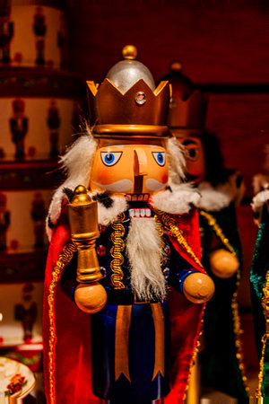 A wooden nutcracker soldier wearing a regal crown and a red cape is prominently displayed, holding a gold staff.の写真素材