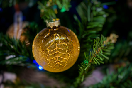 A golden ornament with a leaf design hangs on a Christmas tree,の写真素材