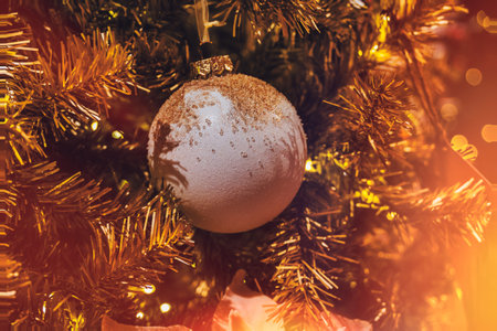 A glittering Christmas ornament hangs on a tree adorned with golden tinsel.の写真素材