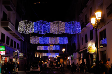 Colorful geometric lights hang above a lively urban street, illuminating the night scene Alicante spainの写真素材