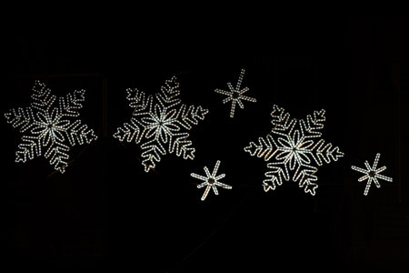 Twinkling christmas lights form the shape of four glowing snowflakesの写真素材