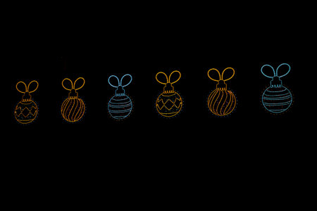 Neon outlines of Christmas tree bauble are arranged in a row against a black background.の写真素材