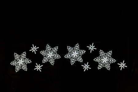 Twinkling christmas lights form the shape of four glowing snowflakesの写真素材