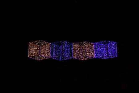 Colorful geometric lights hang above a lively urban street, illuminating the night scene Alicante spainの写真素材