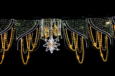 Brilliantly lit decorative lights hang in an intricately pattern, featuring strands of gold and a central star-shaped designの写真素材