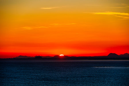 A serene sunset casts a warm orange glow over the horizonの写真素材