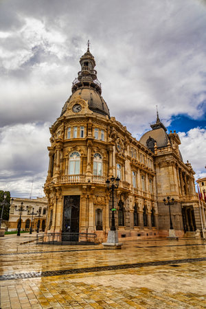 An ornate historic building stands majestically under a partly cloudy sky, featuring intricately architectural details and a prominent clock towerの写真素材