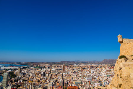 A panoramic view of Alicante with sprawling urban buildings under a clear blue sky.