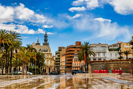 A vibrant cityscape features a mix of historic and modern architecture under a bright blue sky with scattered cloudsの写真素材