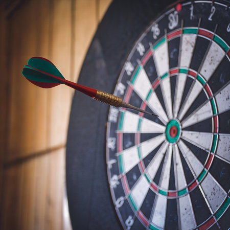 A dart is perfectly hitting the bullseye on a traditional dartboard.の素材