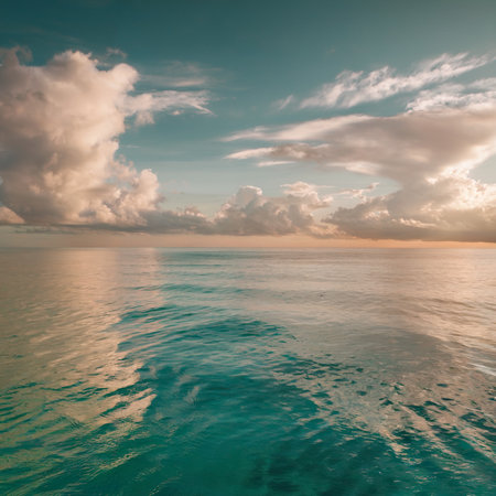 A serene seascape extends to the horizon, with calm turquoise waters reflecting the soft, golden light of the setting sun.の素材