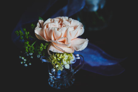 A soft peach rose blooms elegantly in a small glass vase.