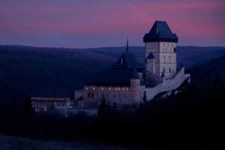 Karlstejn castle in winter time in warm morning sun with shining windows, czech republic