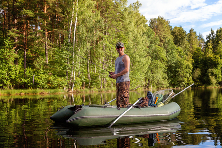 A fisherman is fishing in a boat on a beautiful lakeの写真素材