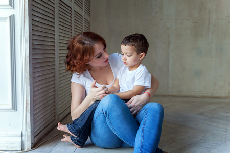 Young mother holding her child. Woman and little boy relax in a bright room. Happy family at home. Young mother playing whith her sonの写真素材