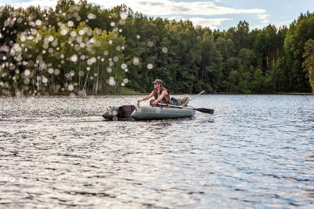 A fisherman is fishing in a boat on a beautiful lakeの写真素材