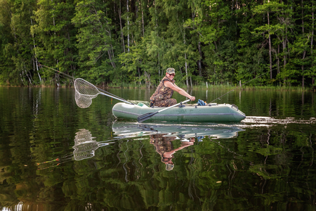 A fisherman is fishing in a row boat on a beautiful lakeの写真素材