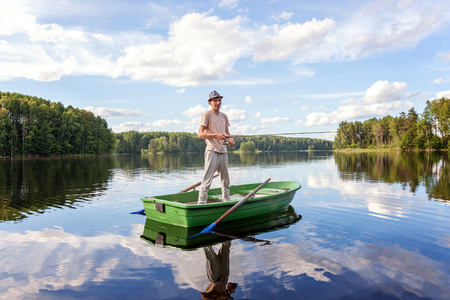 A fisherman is fishing in a wooden boat on a beautiful lakeの写真素材