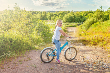 Happy child riding bike. Young girl on bicycle in sunny summer park. Healthy school children summer activity. Kids playing and cycling outdoors. Little girl learns to keep balance while riding bicycleの写真素材