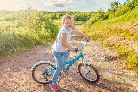 Happy child riding bike. Young girl on bicycle in sunny summer park. Healthy school children summer activity. Kids playing and cycling outdoors. Little girl learns to keep balance while riding bicycleの写真素材