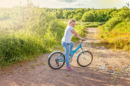 Happy child riding bike. Young girl on bicycle in sunny summer park. Healthy school children summer activity. Kids playing and cycling outdoors. Little girl learns to keep balance while riding bicycleの写真素材