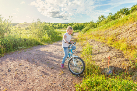 Happy child riding bike. Young girl on bicycle in sunny summer park. Healthy school children summer activity. Kids playing and cycling outdoors. Little girl learns to keep balance while riding bicycleの写真素材