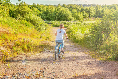 Happy child riding bike. Young girl on bicycle in sunny summer park. Healthy school children summer activity. Kids playing and cycling outdoors. Little girl learns to keep balance while riding bicycleの写真素材